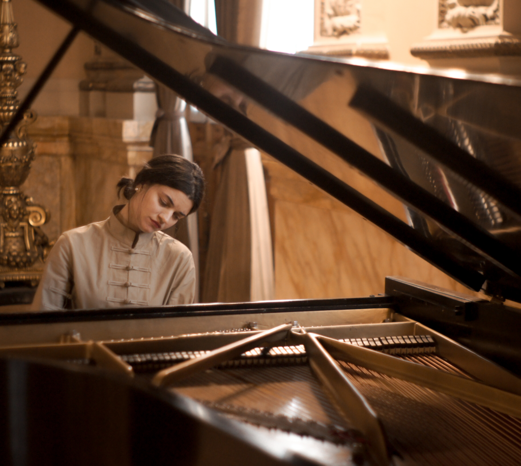 Ana Gabriela Fernández at the piano in a classical architectural setting.